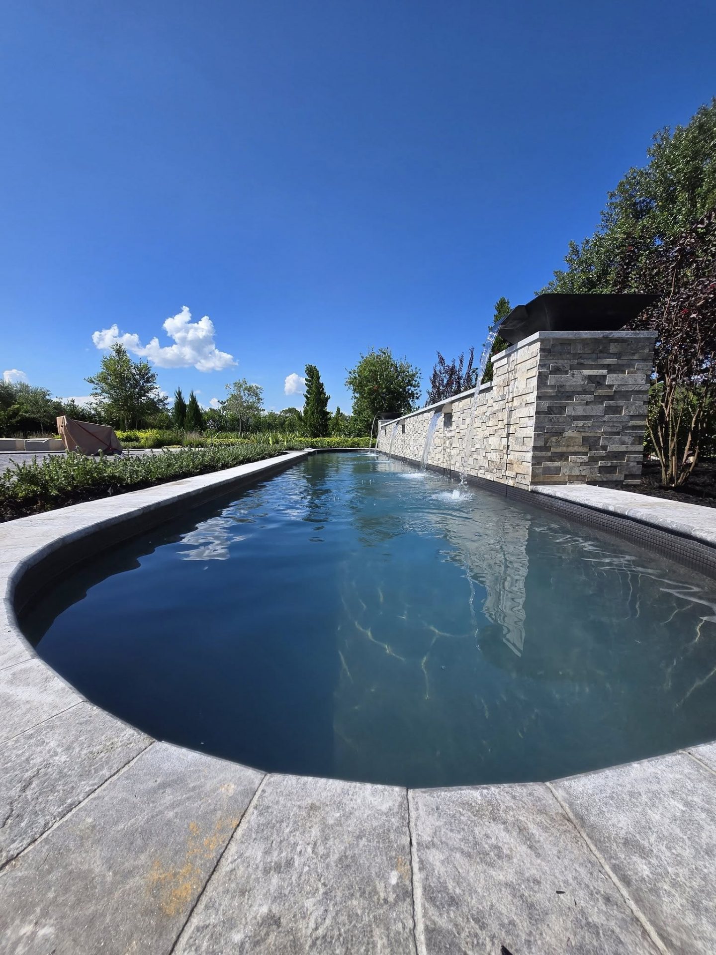 Infinity pool with clear sky and stone wall.